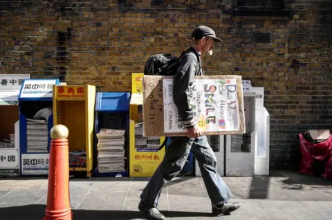 Nina Sherman A rough sleeper carries a homemade motivational placard.