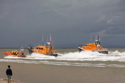 CJ Photo Lifeboats navigate offshore, watched by a young boy