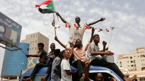 Getty Images Sudanese people celebrate in the streets of Khartoum after ruling generals and protest leaders announced they have reached an agreement on the disputed issue of a new governing body on July 5, 2019. - The landmark agreement came after two days of talks following the collapse of the previous round of negotiations in May over who should lead the new ruling body -- a civilian or soldier. "The two sides agreed on establishing a sovereign council with a rotating military and civilian (presidency) for a period of three years or little more," African Union mediator Mohamed El Hacen Lebatt told reporters