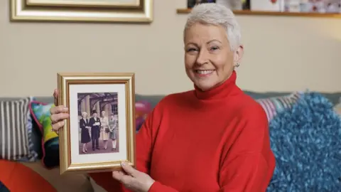 PA Media Broadcaster Pamela Ballantine, who becomes an MBE, with a photo of her family at Buckingham Palace