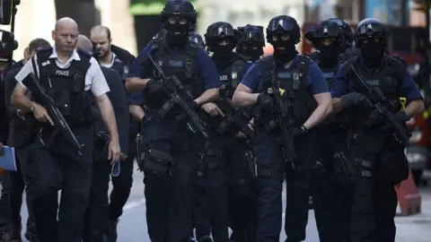 AFP/Getty Images Armed police officers patrol London's Borough Market on the morning after Saturday's attacks