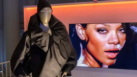 V&A Rihanna's face on a screen behind a mannequin wearing one of her outfits