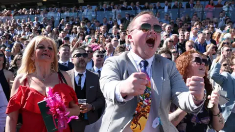 Reuters A man clenches his fists in celebration as racegoers react at Aintree on Grand National day.