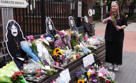 PA Media Floral tributes are left on the Black Sabbath Bridge bench on Broad Street in Birmingham, following the death of Black Sabbath frontman Ozzy Osbourne aged 76. Picture date: Wednesday July 23, 2025.
