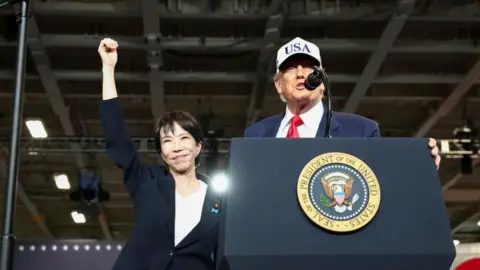 Reuters US President Donald Trump speaks to US Navy sailorin Japan, as Japanese Prime Minister Sanae Takaichi gestures alongside him